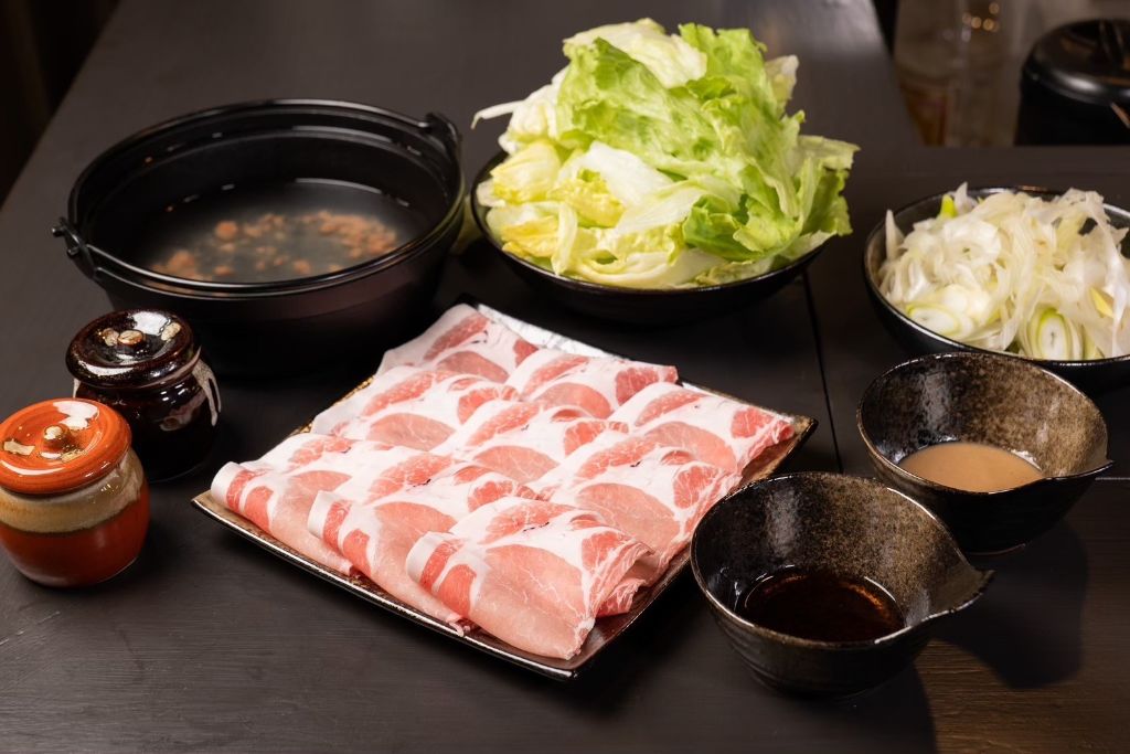 梅出汁を張った鍋と、薄切りの豚肉、レタス、長ねぎ、つけだれをそろえた梅出汁しゃぶしゃぶの一式